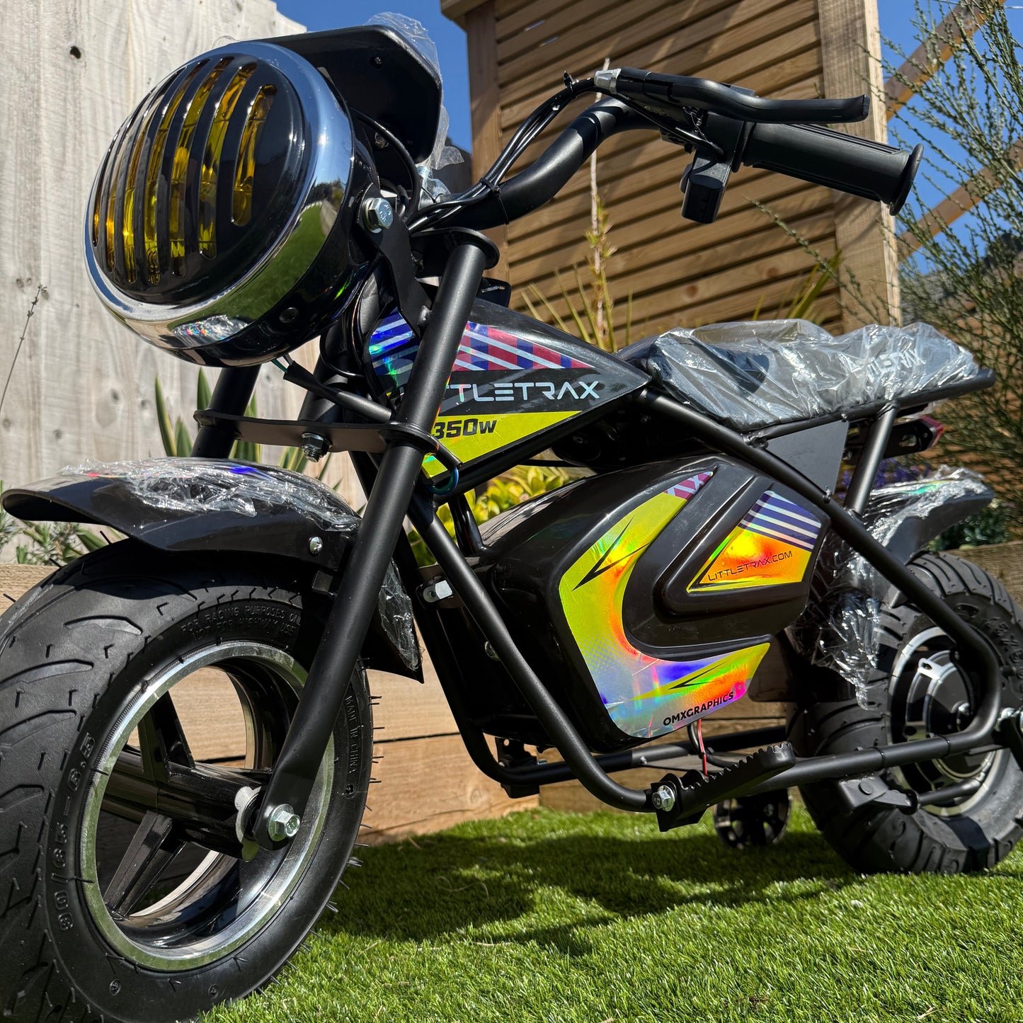Small electric bike with colorful design on a wooden deck and grass background